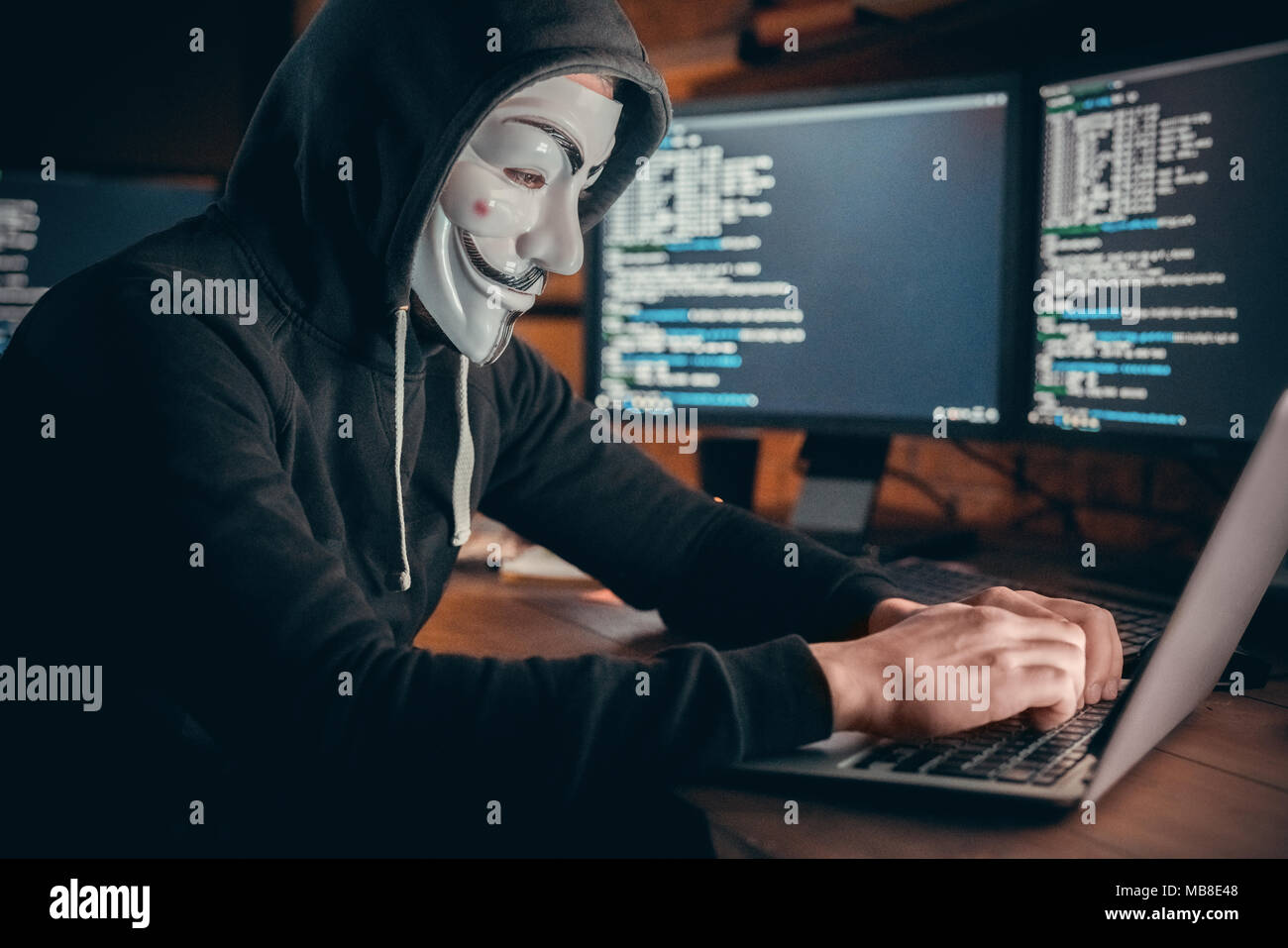 Jeune homme hacker financière au bureau assis à table système hacking typing on laptop Banque D'Images