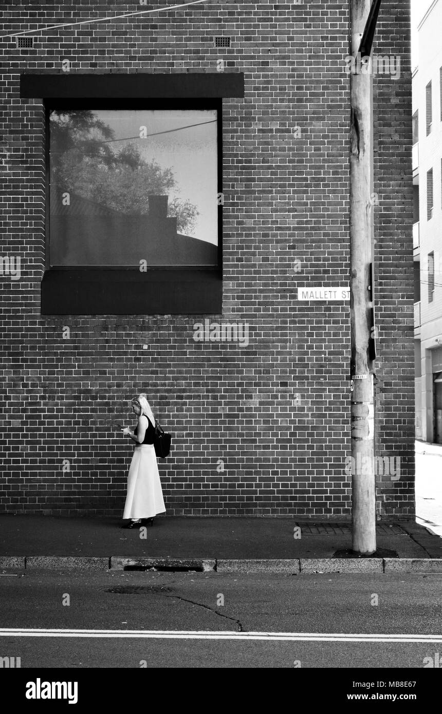 Femme isolée à distance sociale dans la jupe blanche à vérifier le téléphone dans la rue Banque D'Images