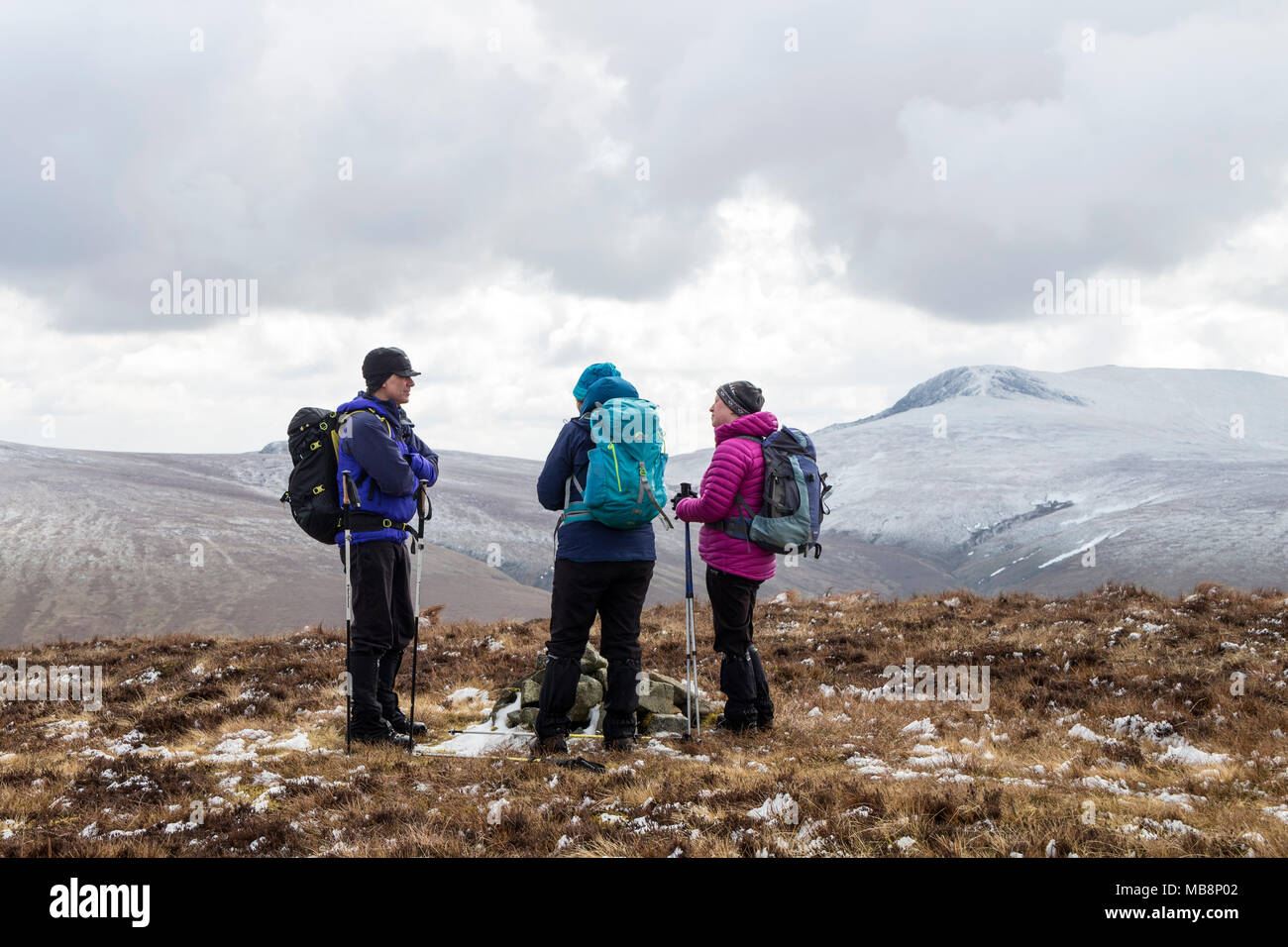 Trois marcheurs chatter sur le sommet de la hauteur de Coombs avec les pentes nord de Blencathra comme toile de fond, Lake District, Cumbria, Royaume-Uni. Banque D'Images