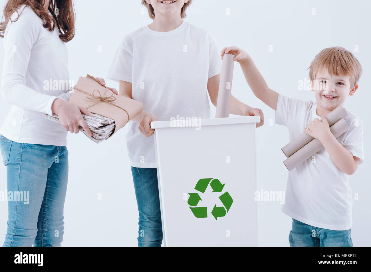 Enfants heureux la ségrégation des déchets de papier dans une poubelle blanc Banque D'Images