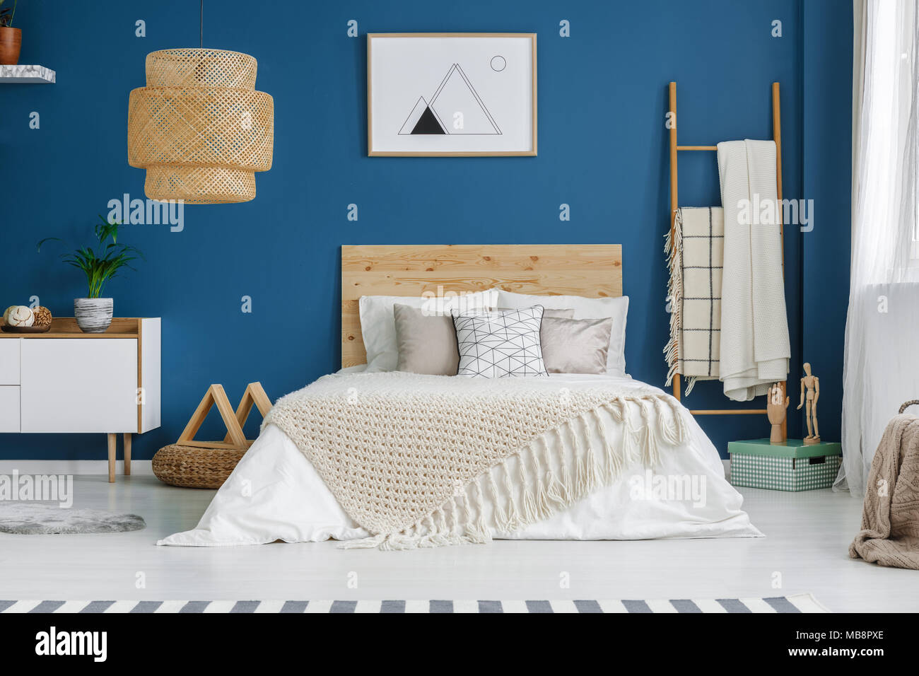 Couverture tricot sur lit en bois en chambre bleue avec intérieur affiche  sur le mur et la lampe Photo Stock - Alamy