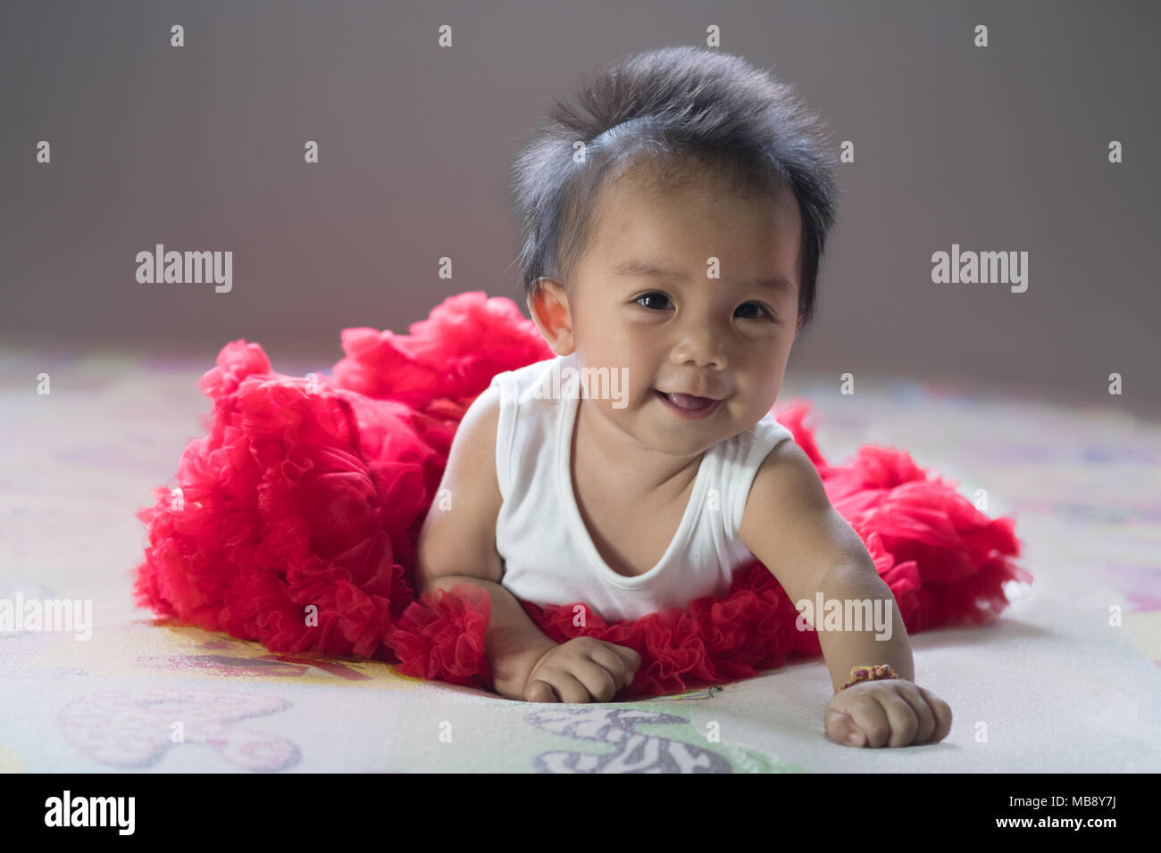 Asian new born baby sit et sourire sur un lit dans la chambre. Banque D'Images