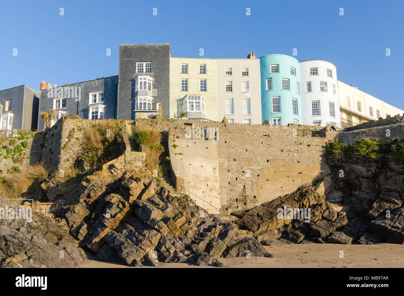 Maisons colorées donnant sur la plage de Tenby, château dans le soleil du matin Banque D'Images