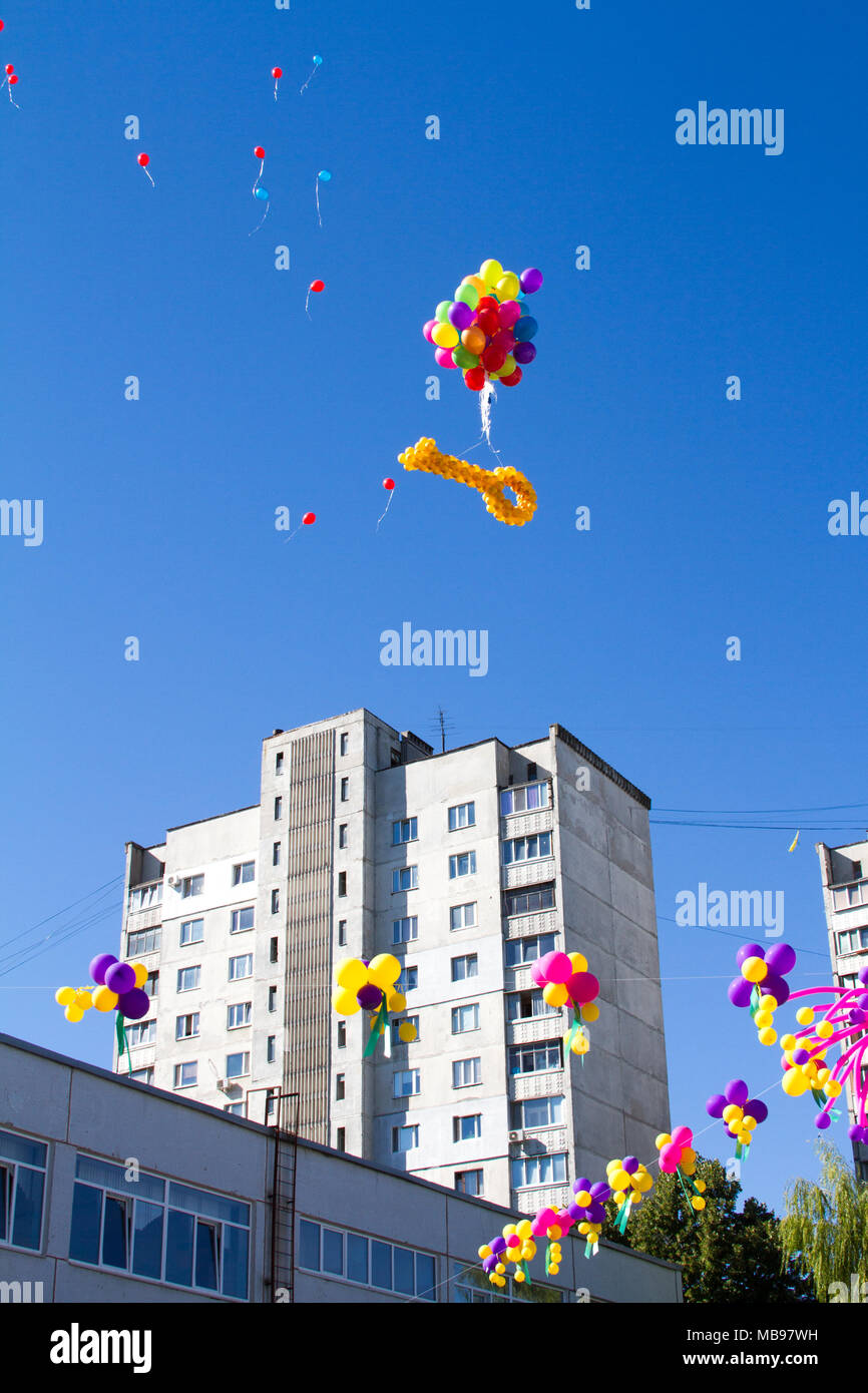 Colorful ballons gonflables multicolores voler dans l'air à l'arrière-plan d'arbres et de ciel bleu pendant le festival de fête. Saluer en ciel de balloo colorés Banque D'Images