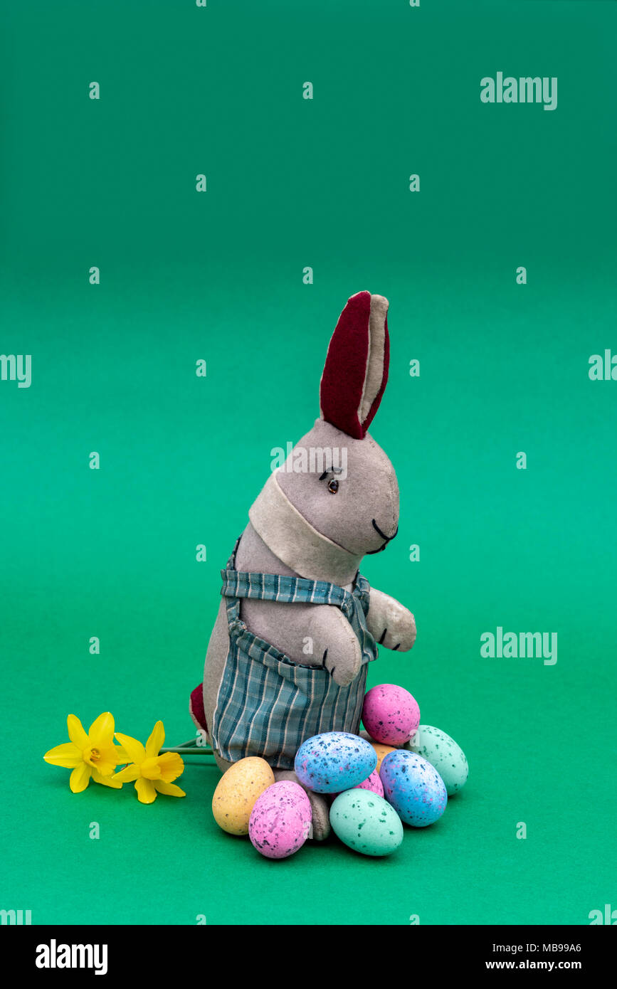Vintage toy lapin, bunny, avec une pile d'oeufs de Pâques au chocolat. Banque D'Images