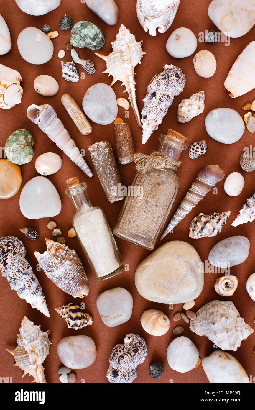 Modèle de sable dans les bouteilles en verre, des coquillages et des pierres sur le fond de papier brun, de mise à plat Banque D'Images