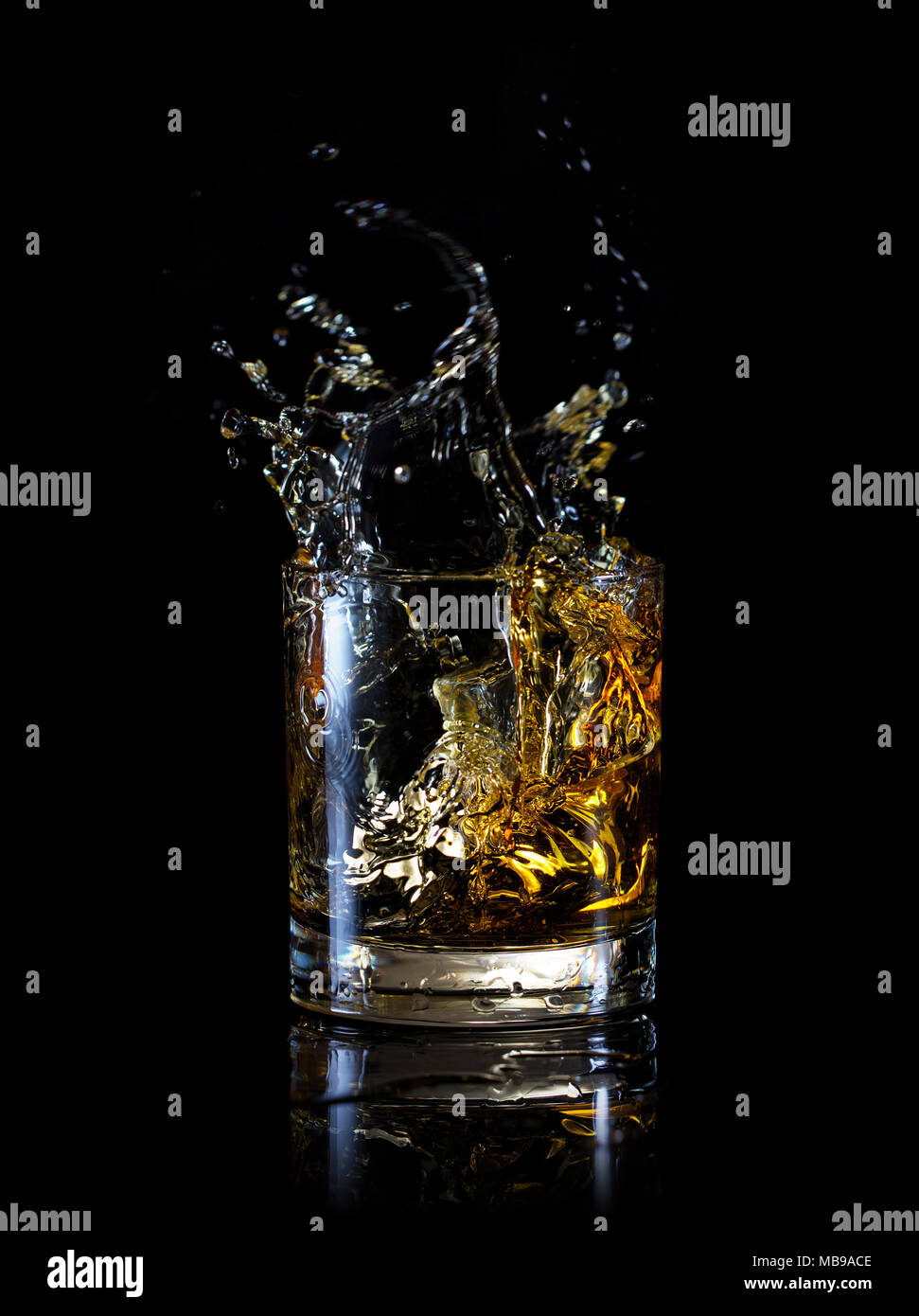 Splash en verre de whisky isolé sur un fond noir Banque D'Images