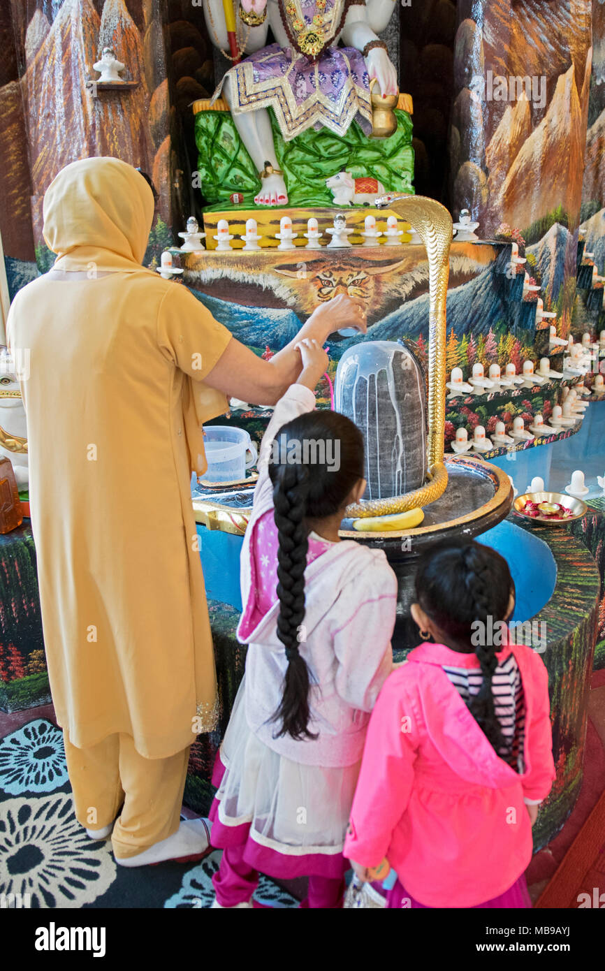 Une femme hindoue et ses enfants faire une offrande au dieu Shiva Mandir Tulsi au sud de Richmond Hill, Queens, New York. Banque D'Images
