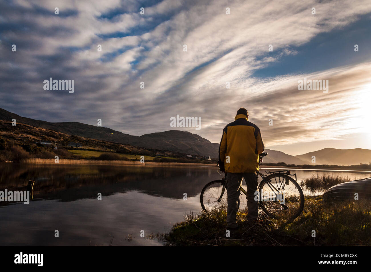 Un cycliste s'arrête pour regarder le coucher du soleil à Ardara, comté de Donegal, Irlande Banque D'Images