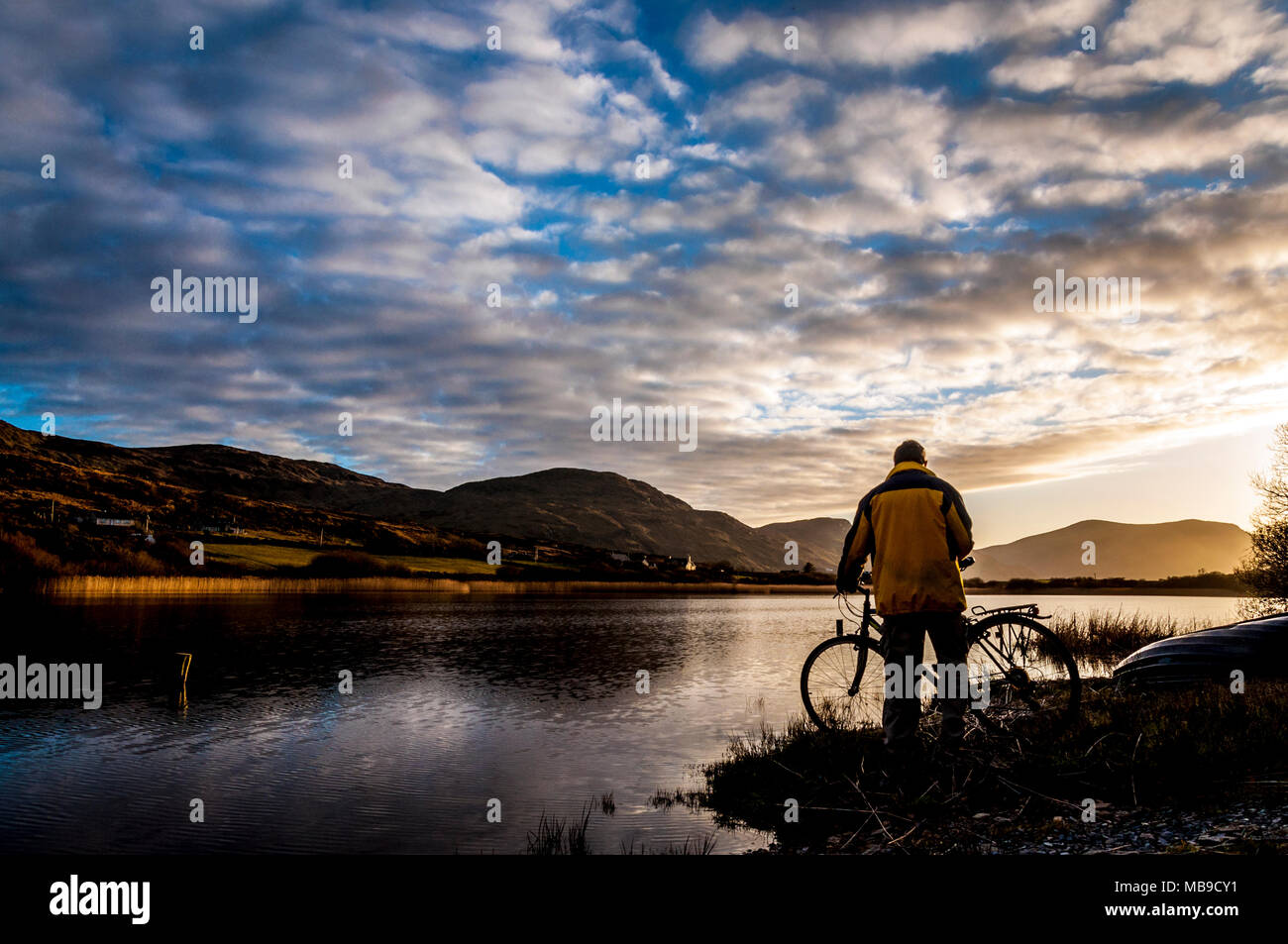 Un cycliste s'arrête pour regarder le coucher du soleil à Ardara, comté de Donegal, Irlande Banque D'Images