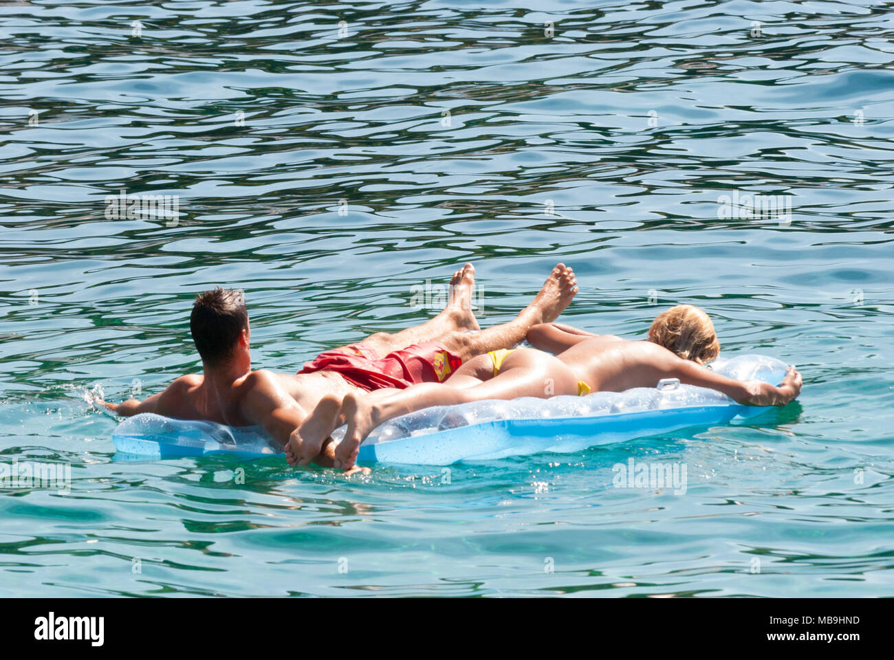 Jeune couple flottant sur lilos dans la mer dans le soleil d'été. Banque D'Images