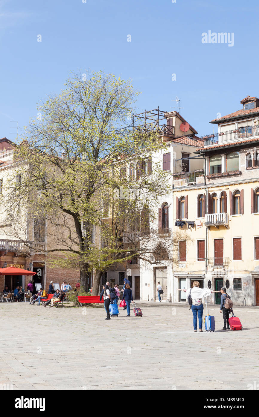 Campo San Polo, San Polo, Venise, Vénétie, Italie au printemps avec les  touristes tirant leurs valises sur la place et les sections locales à vous  détendre sous les arbres Photo Stock -