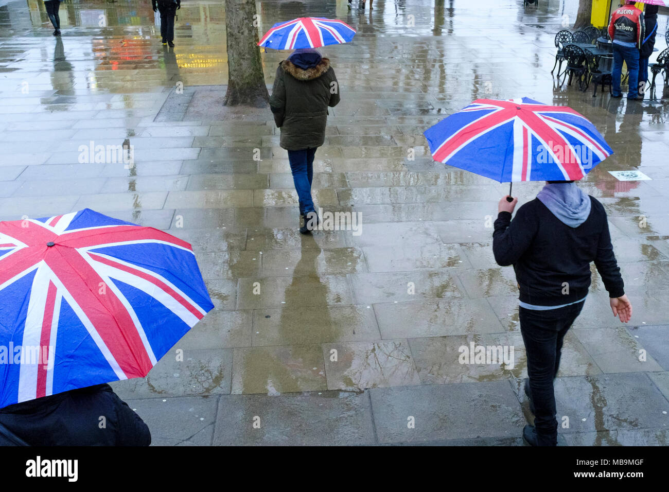 Piétons marchant sous la pluie avec les parapluies Union Jack, Londres, Royaume-Uni Banque D'Images