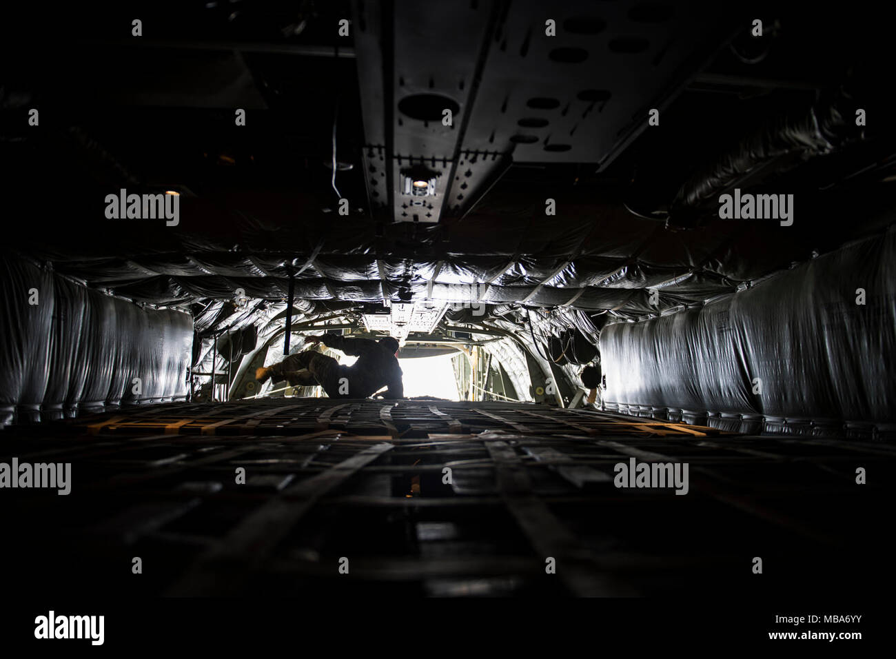Un U.S. Air Force C-130 Hercules de l'arrimeur, affecté à la 746e Escadron de transport aérien expéditionnaire, dirige les opérations de chargement à la base aérienne d'Al Udeid, Qatar, 10 févr. 06, 2018. Les arrimeurs C-130H s'assurer que la cargaison est transportée en toute sécurité et sont responsables d'assurer la livraison rapide de troupes et stratégique tous les types de marchandises. (U.S. Air Force Banque D'Images