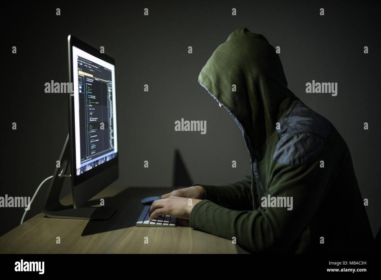 Un hacker dans un capot, sur un fond sombre hacking des réseaux informatiques Banque D'Images