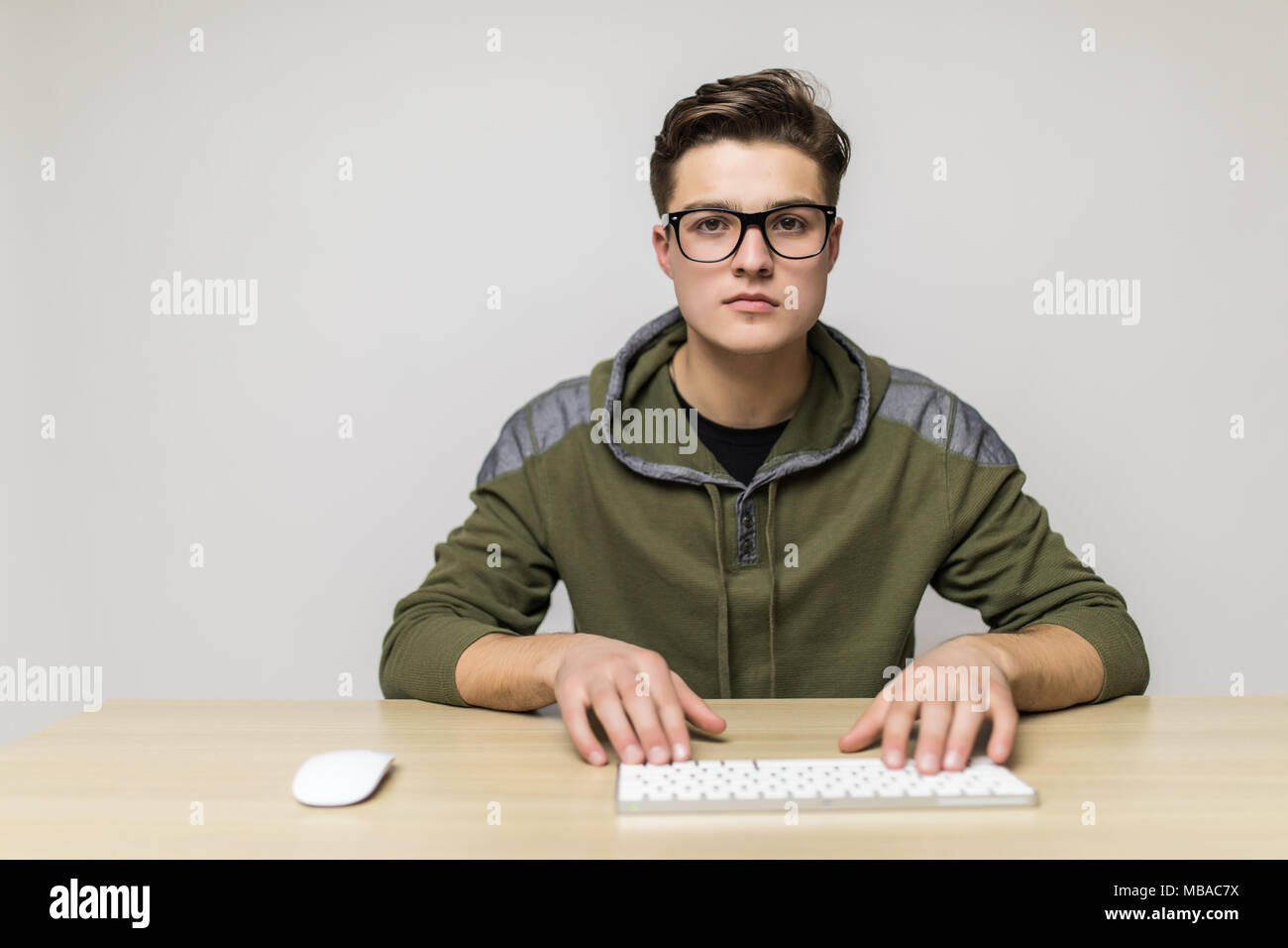 Portrait de jeune homme à table avec les mains sur le clavier et la souris. Banque D'Images