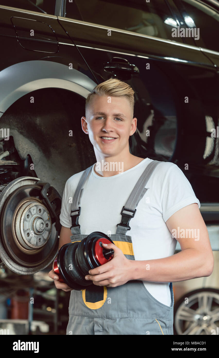 Portrait d'un certain jeune auto mechanic holding un nouveau système de suspension pneumatique Banque D'Images
