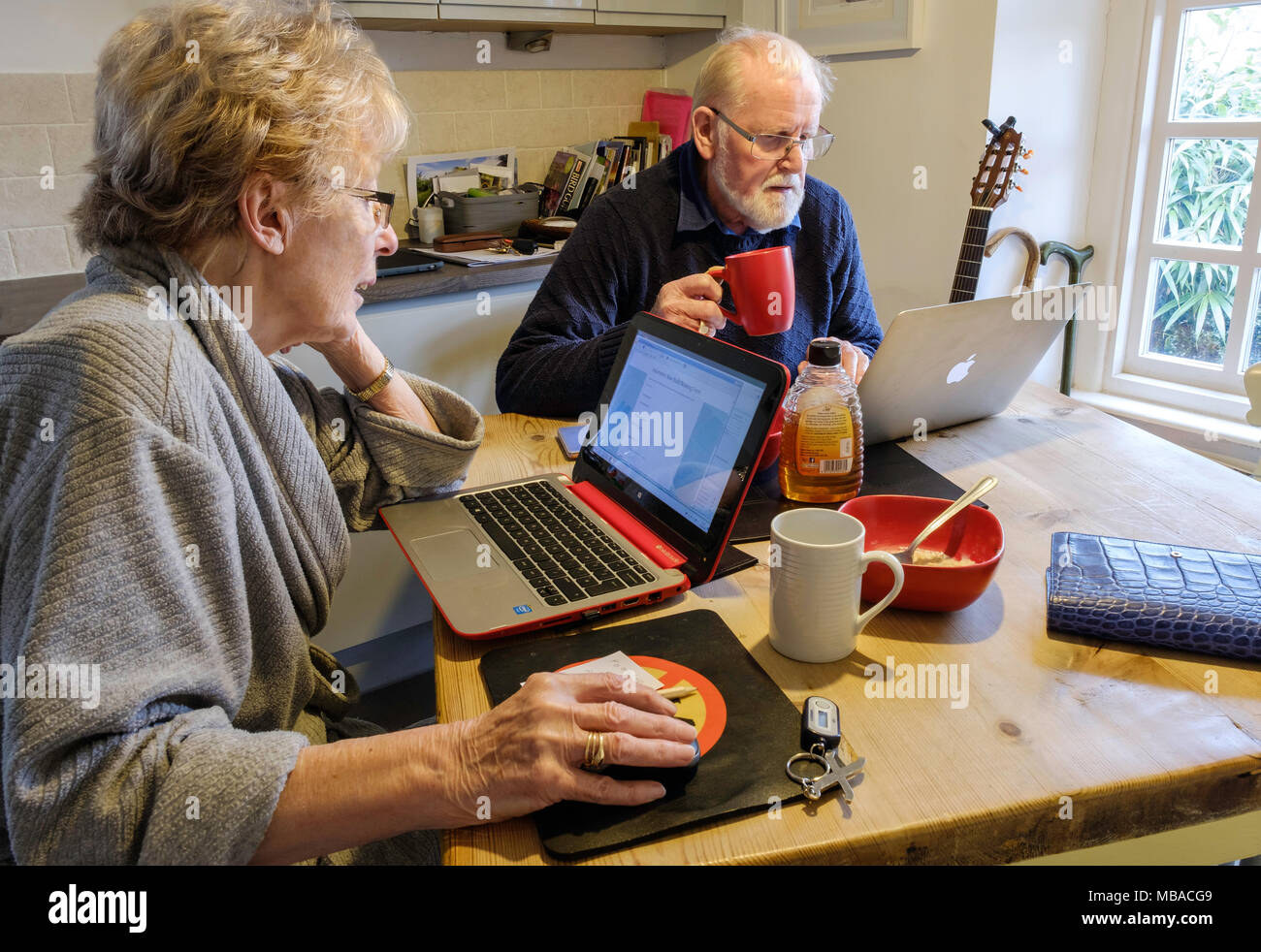 Vieux COUPLE AU PETIT-DÉJEUNER AVEC DES ORDINATEURS Banque D'Images