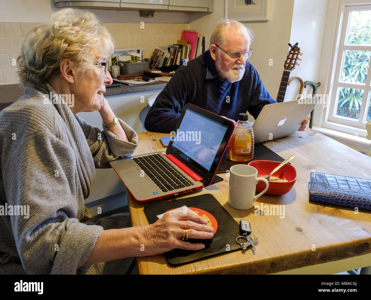 Vieux COUPLE AU PETIT-DÉJEUNER AVEC DES ORDINATEURS Banque D'Images