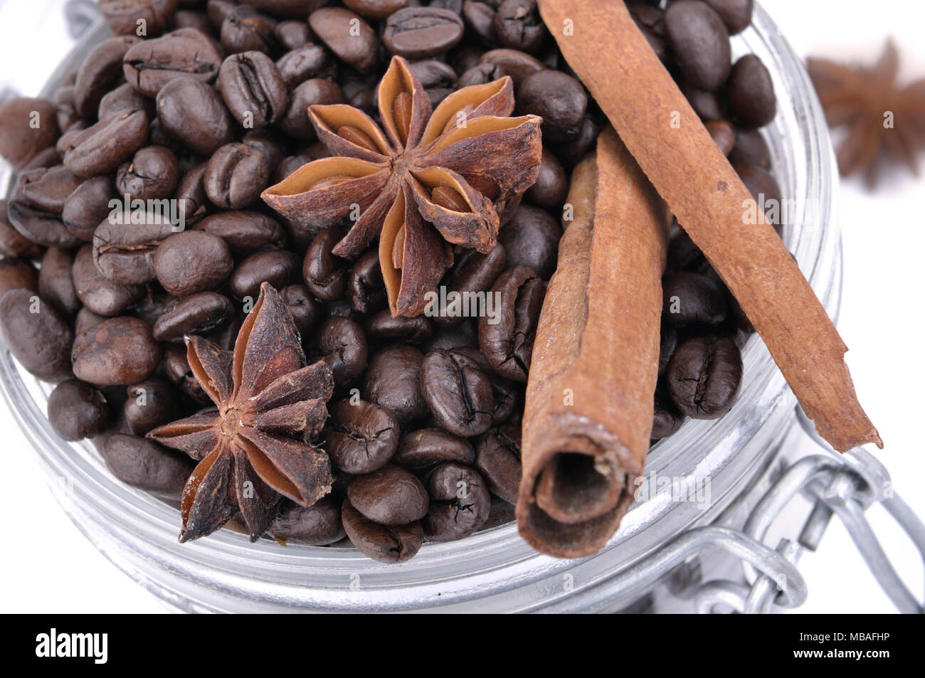 Fermer sur l'anis et la cannelle dans les fèves de café dans un bocal en verre sur fond blanc Banque D'Images
