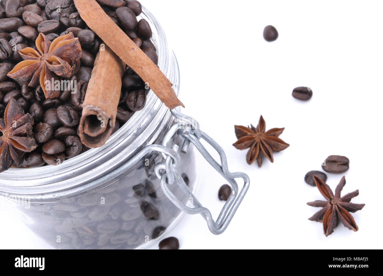 Vue de dessus sur l'anis et la cannelle dans les fèves de café dans un bocal en verre sur fond blanc Banque D'Images