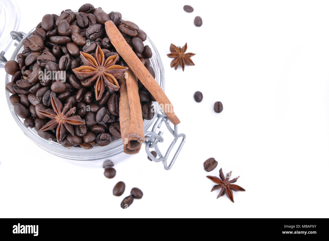 Vue de dessus sur l'anis et la cannelle dans les fèves de café dans un bocal en verre sur fond blanc Banque D'Images