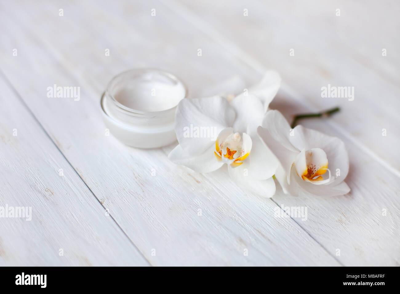 Pot de crème hydratant visage et de belles fleurs orchidée blanche sur fond blanc Banque D'Images