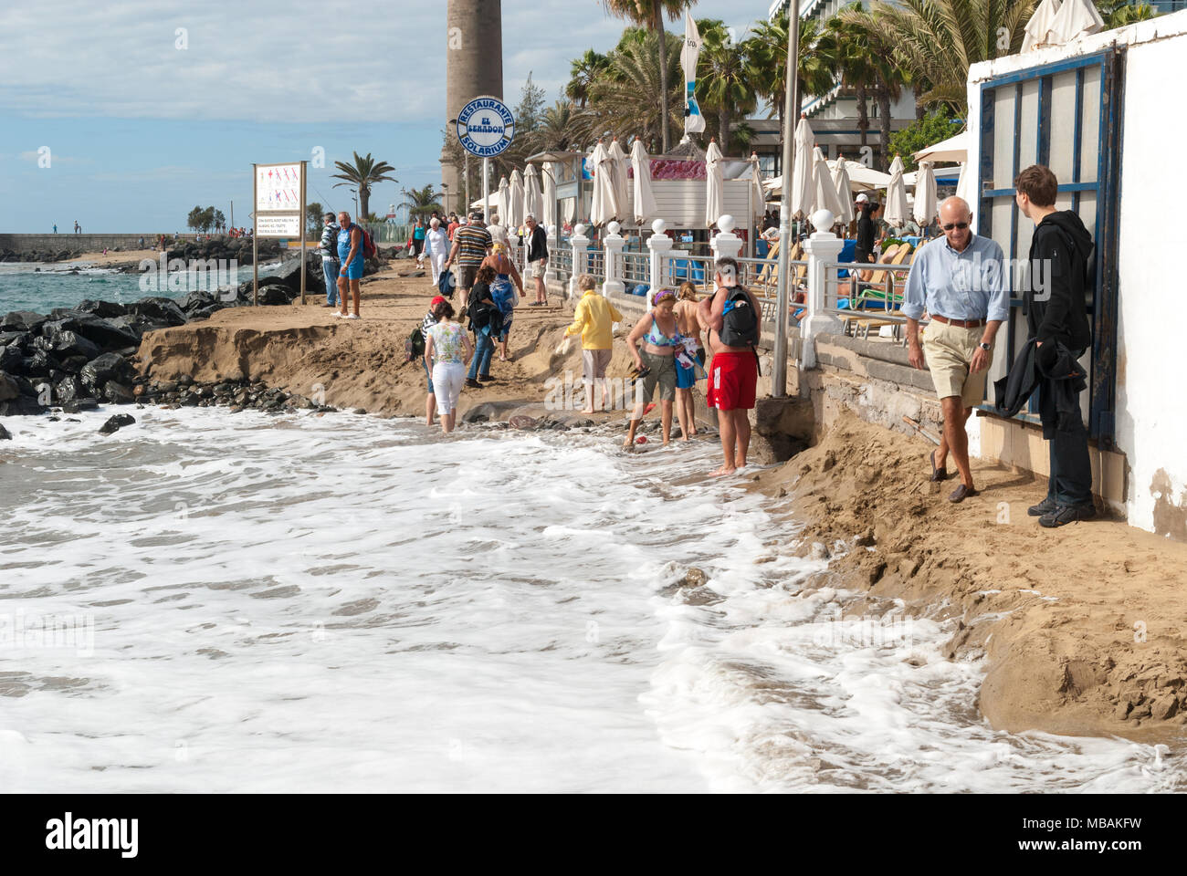 Les gens qui marchent le long de la mer avec la mer à marée haute de prendre une route étroite de passage, Maspalomas, Gran Canaria, Îles Canaries, Espagne Banque D'Images
