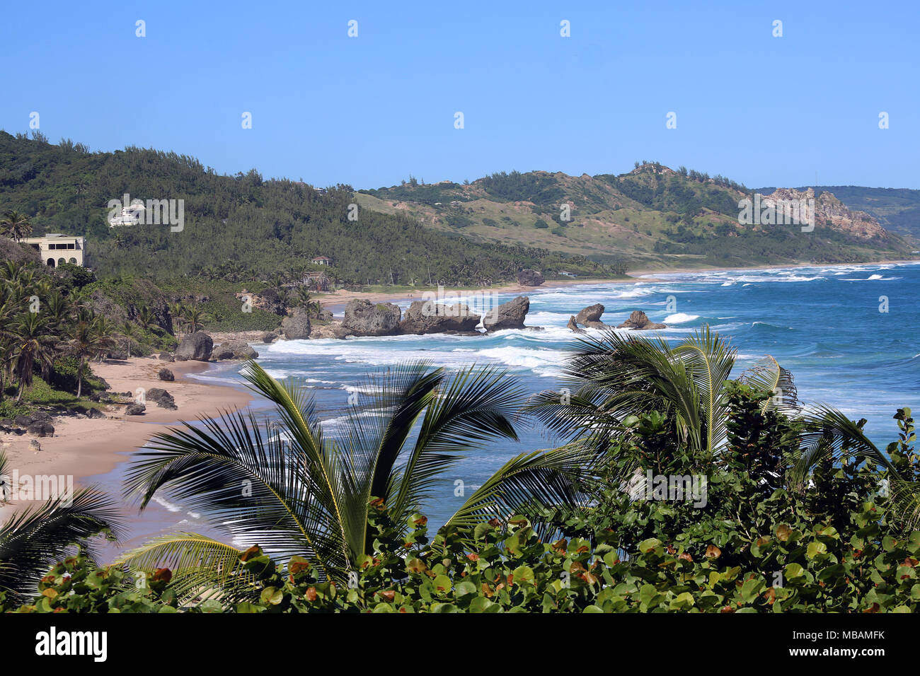 Vagues se brisant entre les roches avec plage de sable sur le rivage de la mer des Caraïbes Banque D'Images