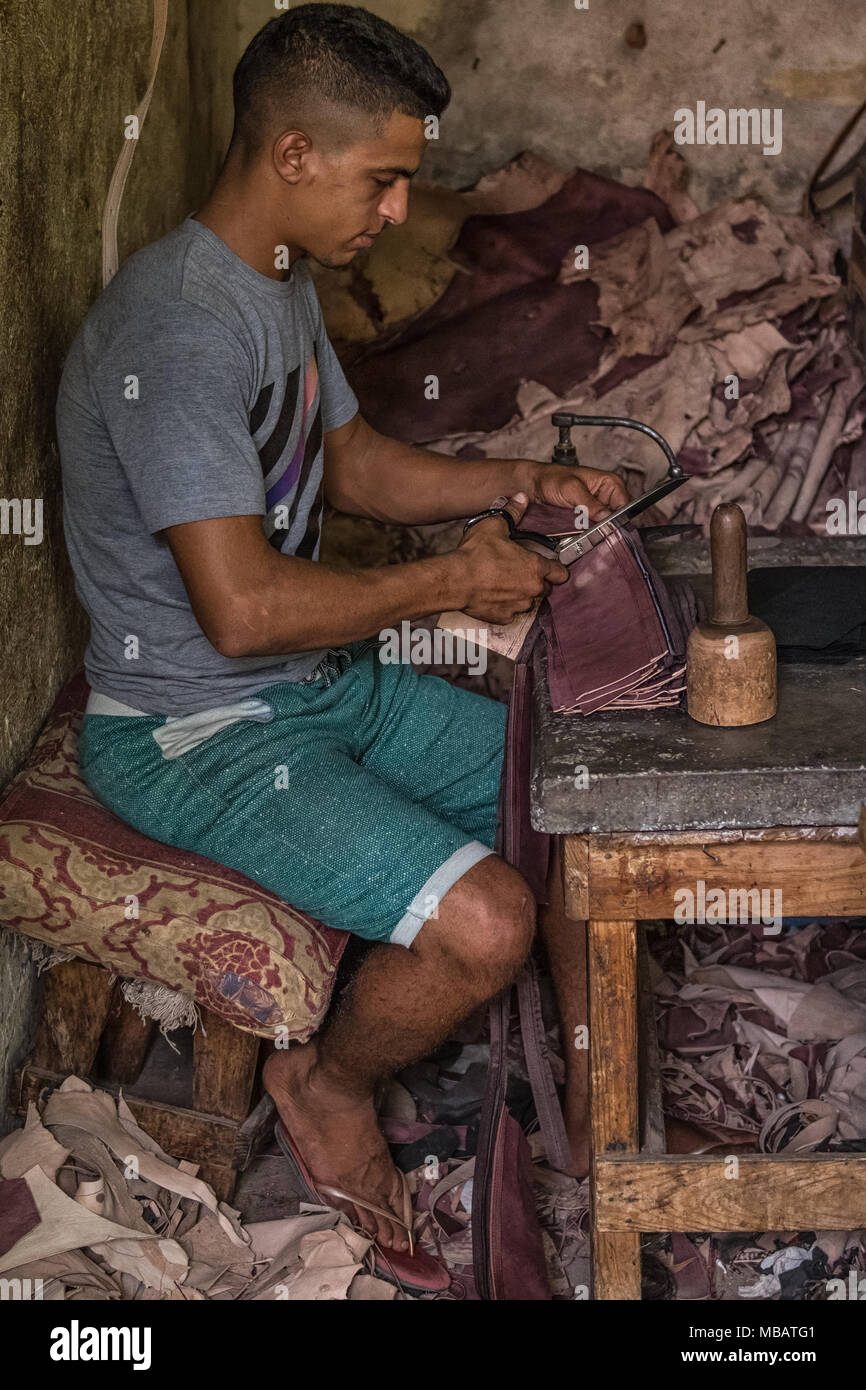 Un homme marocain de coupe en morceaux de cuir Le cuir de district de Marrakech, Maroc. Les pièces de cuir faites main, chaussures, etc. Banque D'Images