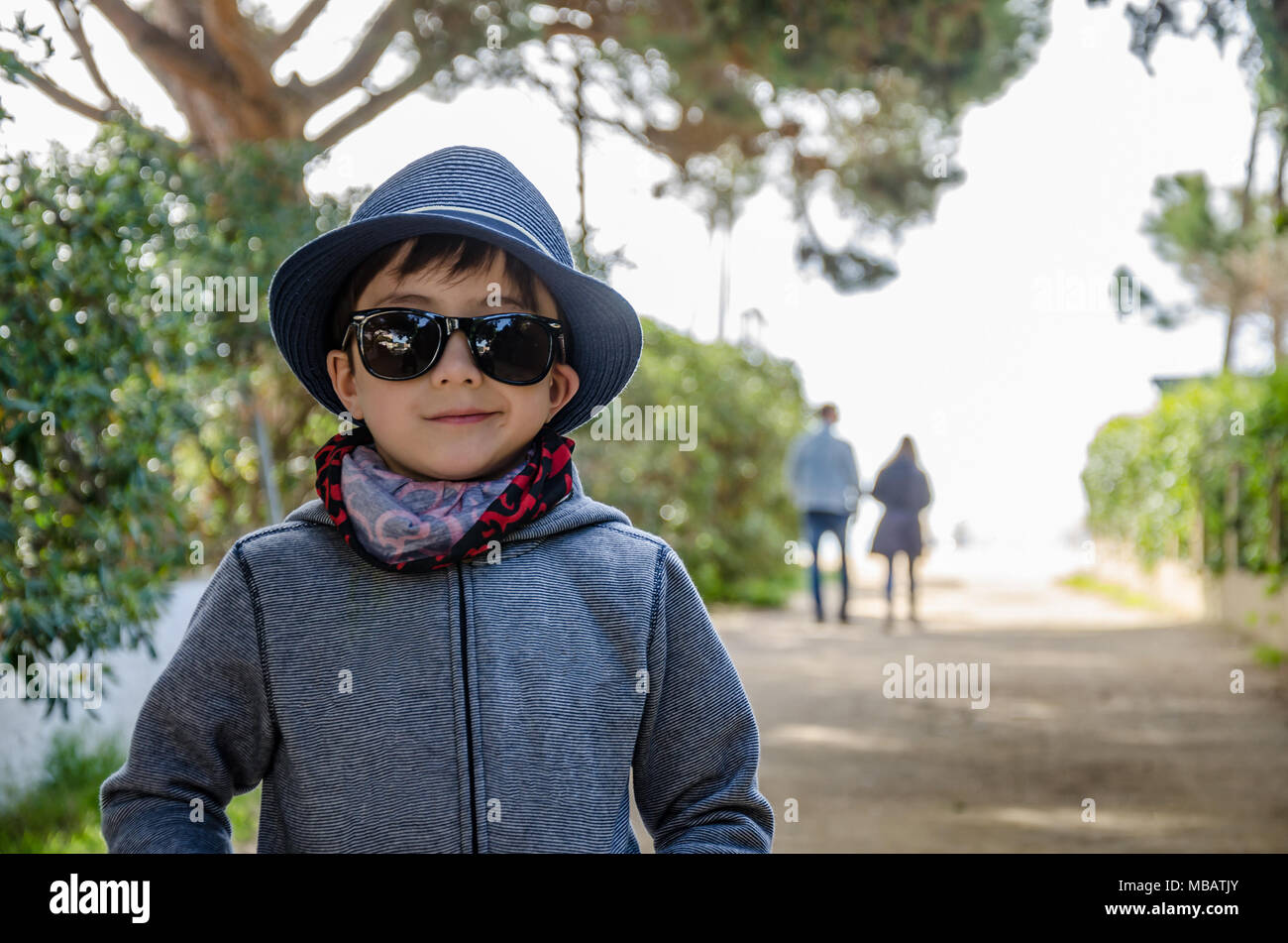 Un portrait d'un jeune garçon portant un bandana, des lunettes de soleil et chapeau d'été. Banque D'Images