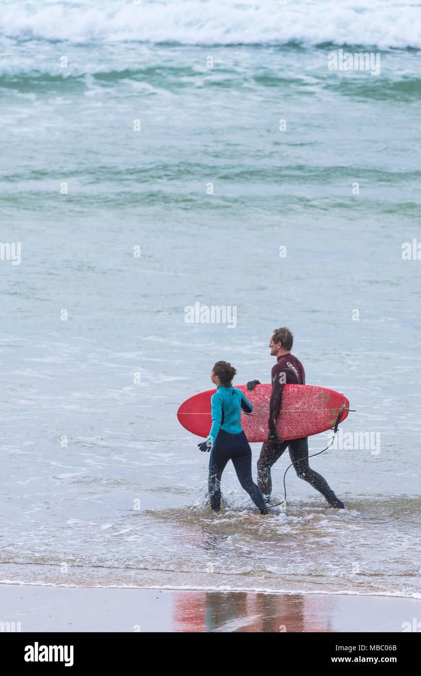 Un instructeur de surf et d'une jeune fille qui marche dans la mer. Banque D'Images