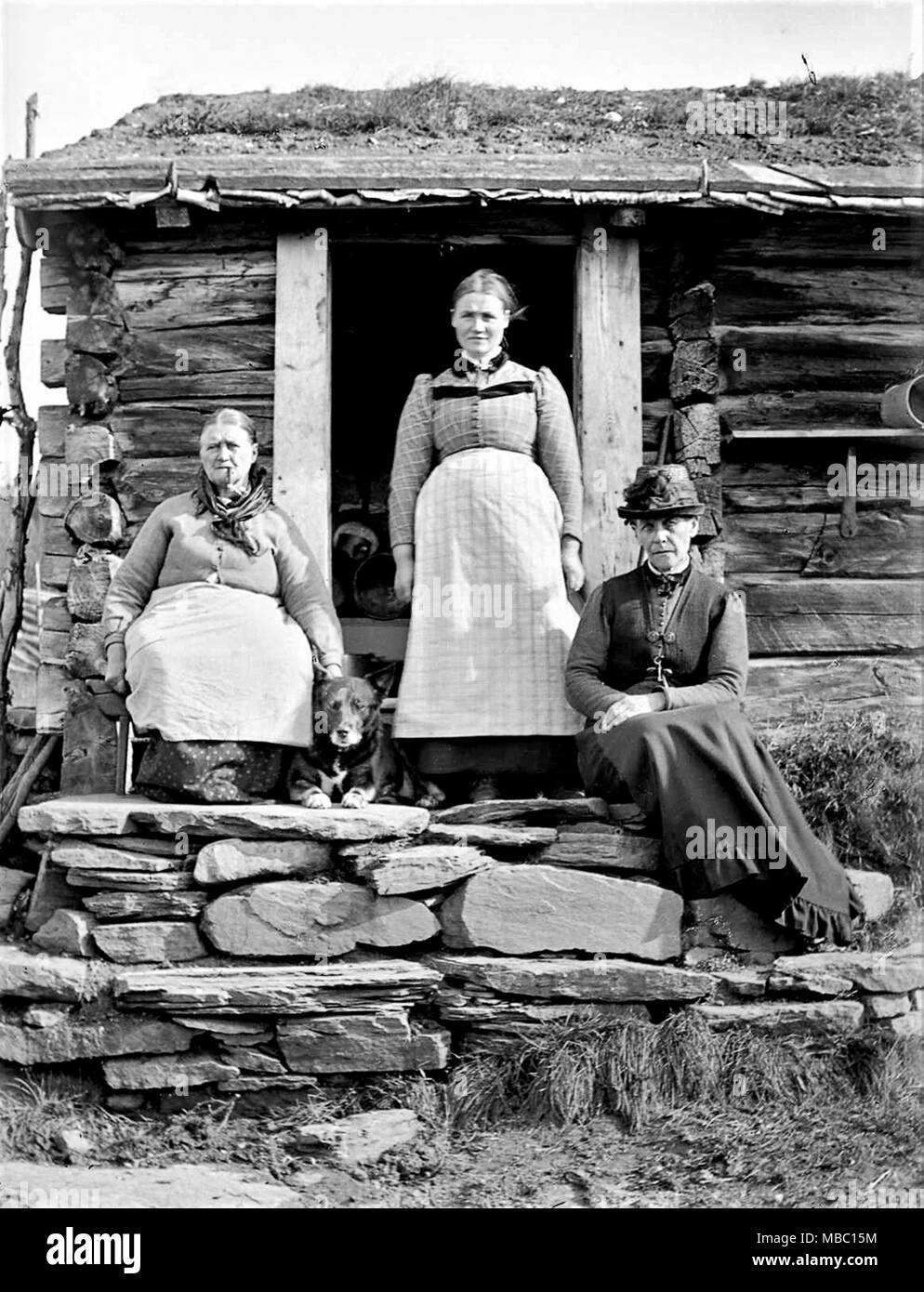 Les femmes norvégiennes assis en dehors de l'espace rural cabane en Norvège 1910 femme sur la gauche a un cigare dans sa bouche. Banque D'Images