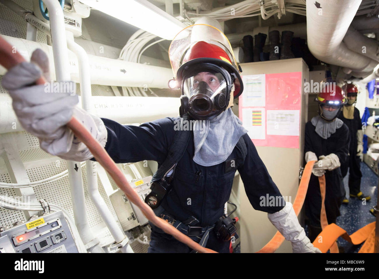 Océan Pacifique (fév. 14, 2018) Seaman Michael King, de Gilbert, Arizona), affectés à la classe Arleigh Burke destroyer lance-missiles USS Dewey (DDG 105), passe un flexible sur une échelle pendant la simulation d'inondation dans un espace d'amarrage. Dewey est sur un déploiement prévu de mener des opérations dans la région Indo-Pacifique. Il permettra également de soutenir le groupe expéditionnaire Wasp (ESG) pour l'avance de la Flotte du Pacifique américaine Up-Gunned concept ESG et va former avec l'avant-déployés dans tous les navires amphibies les zones de mission. (U.S. Navy Banque D'Images