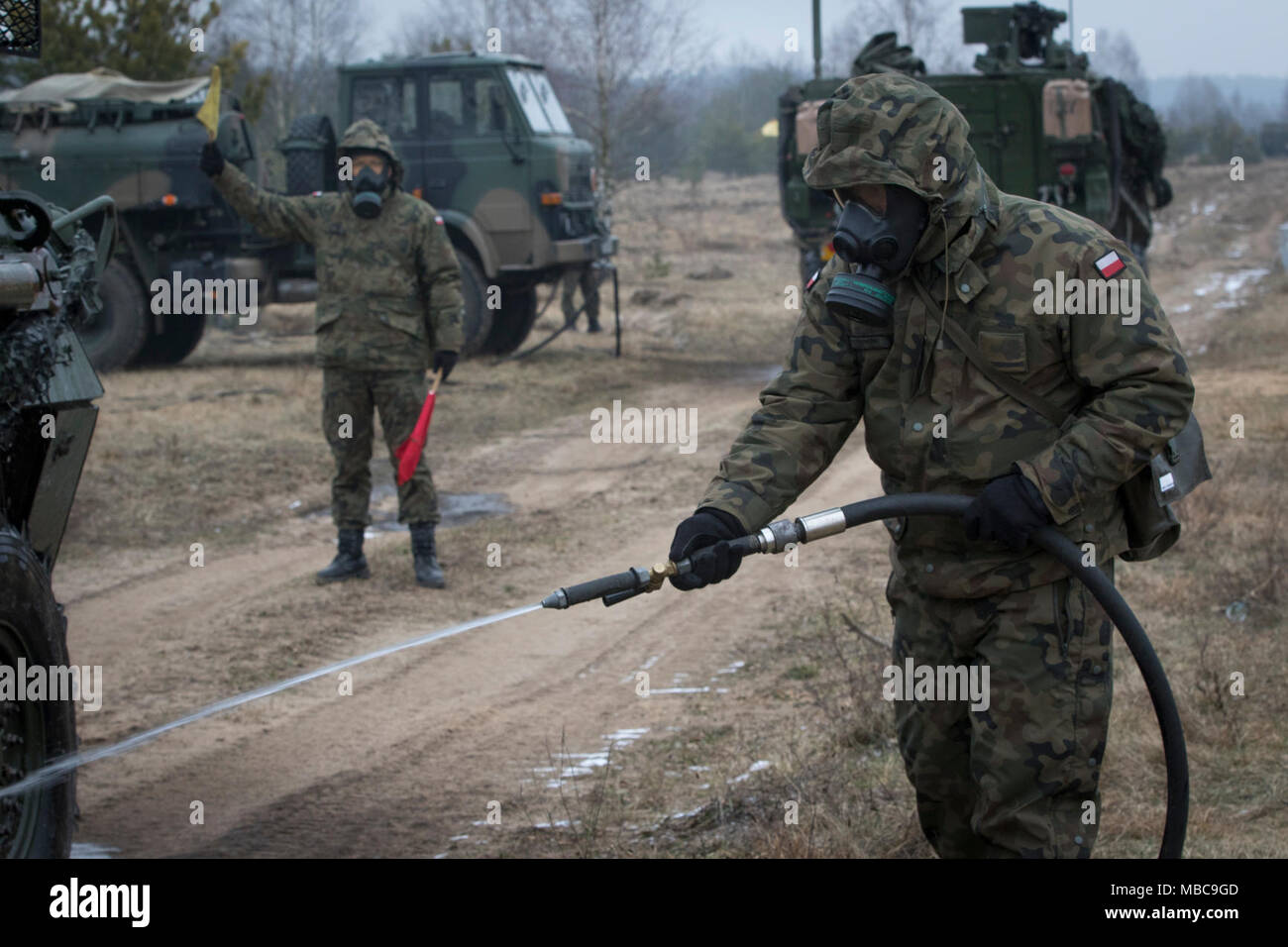 Un soldat polonais avec le 1er Bataillon, 15e Brigade mécanisée, procède à un lavage pour décontaminer un Stryker américain tout en menant à une formation de contamination près de la gamme Bemowo Piskie Domaine de formation, Pologne, 16 février 2018. Ces soldats sont une partie de l'unique groupe de combat multinationales, composé de États-Unis, Royaume-Uni, croate et soldats roumains qui servent avec la 15e Brigade mécanisée polonaise comme une force de dissuasion dans le nord-est de la Pologne à l'appui de l'OTAN vers l'amélioration de la présence. (U.S. Army Banque D'Images
