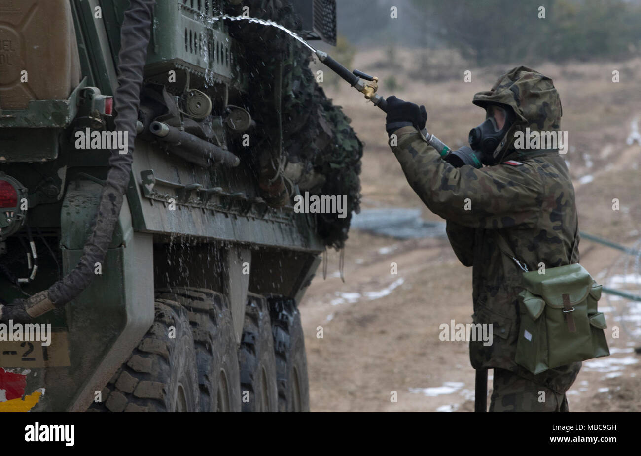 Un soldat polonais avec le 1er Bataillon, 15e Brigade mécanisée, procède à un lavage pour décontaminer un Stryker américain au cours de produit chimique, biologique, radiologique et nucléaire (CBRN) formation à une gamme près de la zone d'entraînement Bemowo Piskie, Pologne, 16 février 2018. Ce soldat est une partie de l'unique groupe de combat multinationales, composé de États-Unis, Royaume-Uni, croate et soldats roumains qui servent avec la 15e Brigade mécanisée polonaise comme une force de dissuasion dans le nord-est de la Pologne à l'appui de l'OTAN vers l'amélioration de la présence. (U.S. Army Banque D'Images