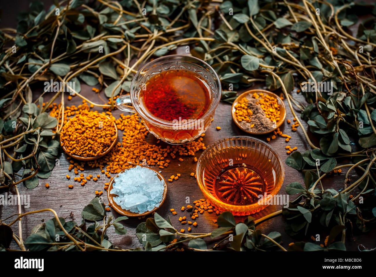 Close up of thé fenugrec avec du miel,sucre,citron et les graines de fenugrec sur une surface en bois foncé en couleurs gothique.Il aide à soulager les crampes menstruelles, lo Banque D'Images