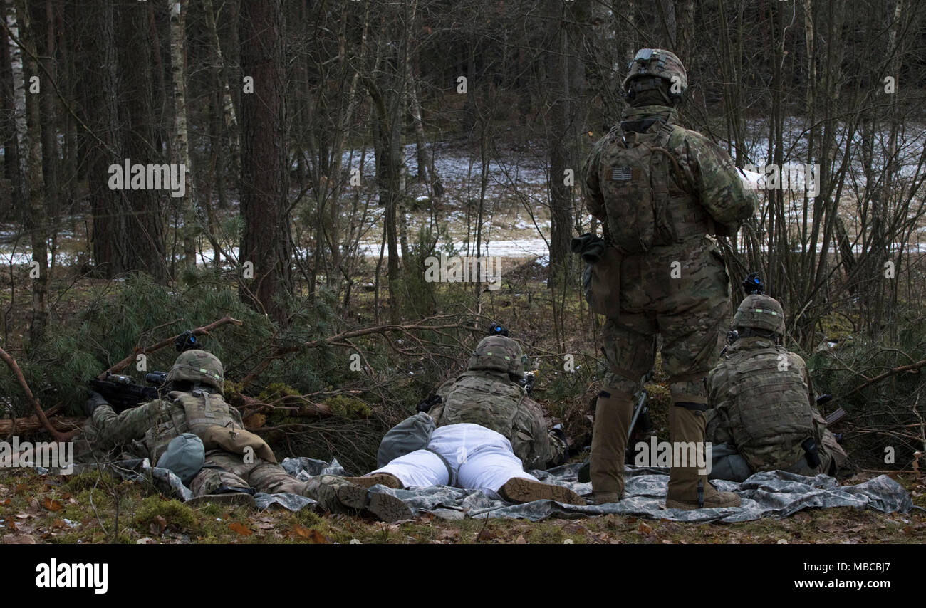 Des soldats américains affectés à la Troupe de fer, 3e Escadron, 2e régiment de cavalerie, tirez sur la sécurité comme son chef d'équipe écrit leurs coordonnées tout en participant à l'exercice de formation de multinationales à Puma une gamme près de la zone d'entraînement Bemowo Piskie, Pologne, le 19 février, 2018. Ces soldats font partie de l'unique, composé de groupe de combat multinationales des États-Unis, du Royaume-Uni, de la Croatie et de soldats roumains qui servent avec la 15e Brigade mécanisée polonaise comme une force de dissuasion dans le nord-est de la Pologne à l'appui de l'OTAN vers l'amélioration de la présence. (U.S. Army Banque D'Images