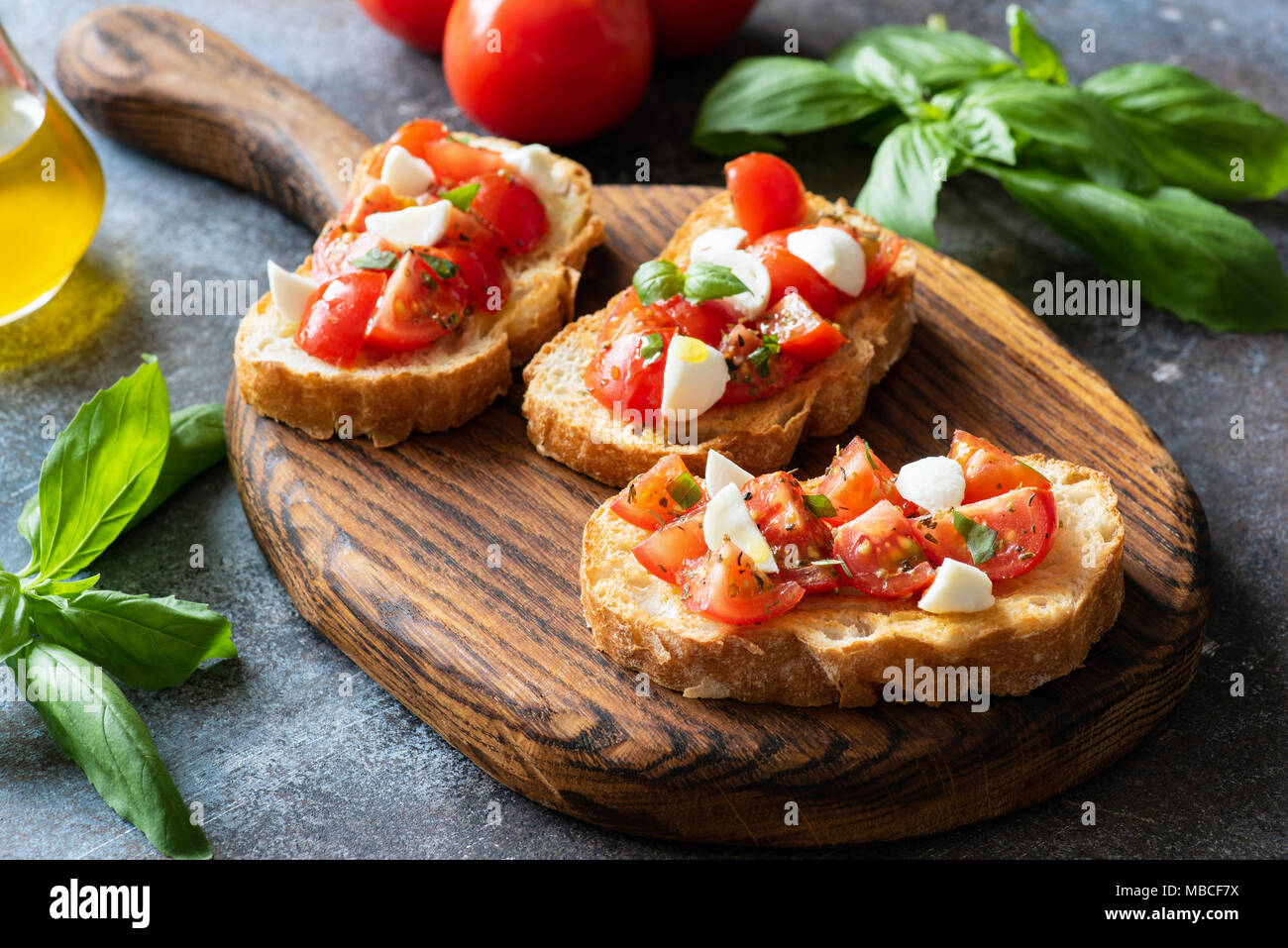Bruschetta à la tomate cerise et de mozzarella sur la planche à découper en bois. La cuisine italienne. Ou Antipasti apéritif Banque D'Images