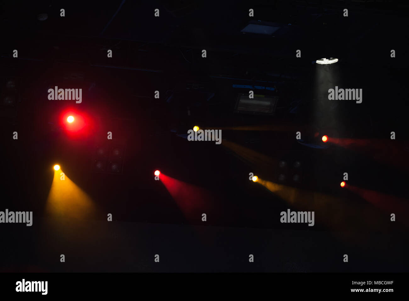 Des spots rouges et jaunes avec des poutres apparentes en fumée sur fond sombre, stade moderne d'équipement d'éclairage Banque D'Images