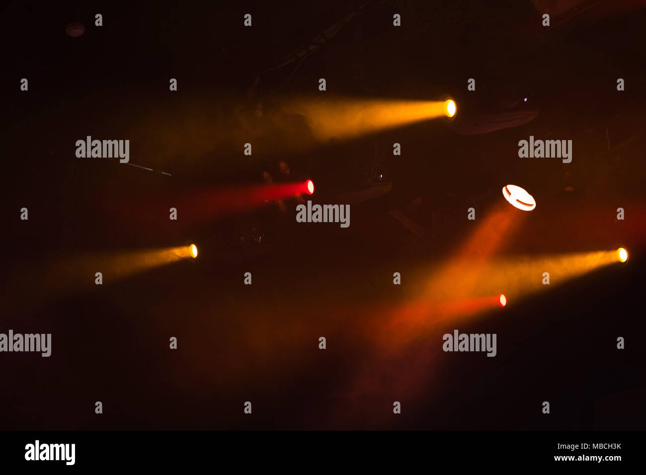 Des spots rouges et orange avec des poutres apparentes en fumée sur fond sombre, stade moderne d'équipement d'éclairage Banque D'Images