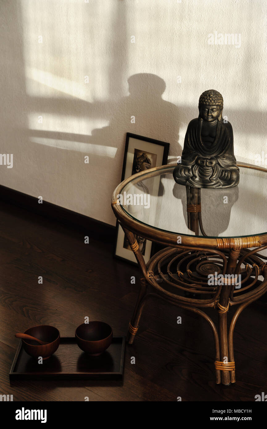 Statuette de Bouddha sur la table. Deux bols sur le plancher. Banque D'Images