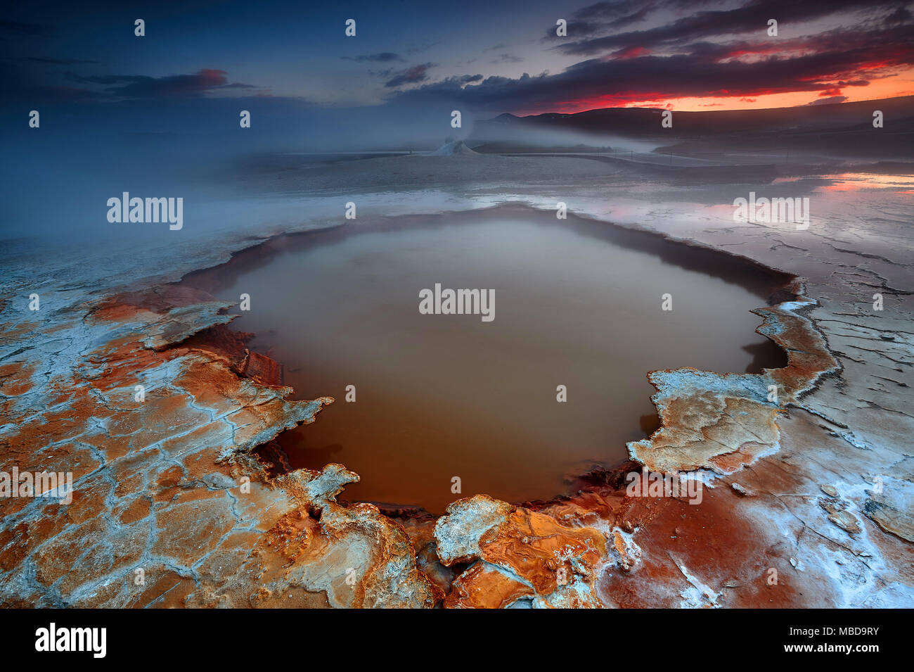 Une source d'eau chaude géothermique @Hveravellir, Islande lors d'un coucher du soleil. La croûte terrestre s'est érodé par le soufre... Banque D'Images