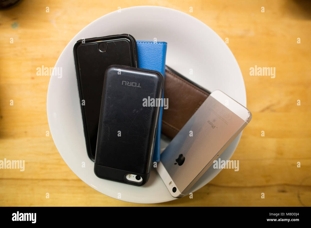Jeune groupe de personnes d'assister à un dîner parti main leurs smartphones dans l'hôte d'un "smartphone" soir, Londres, Royaume-Uni Banque D'Images