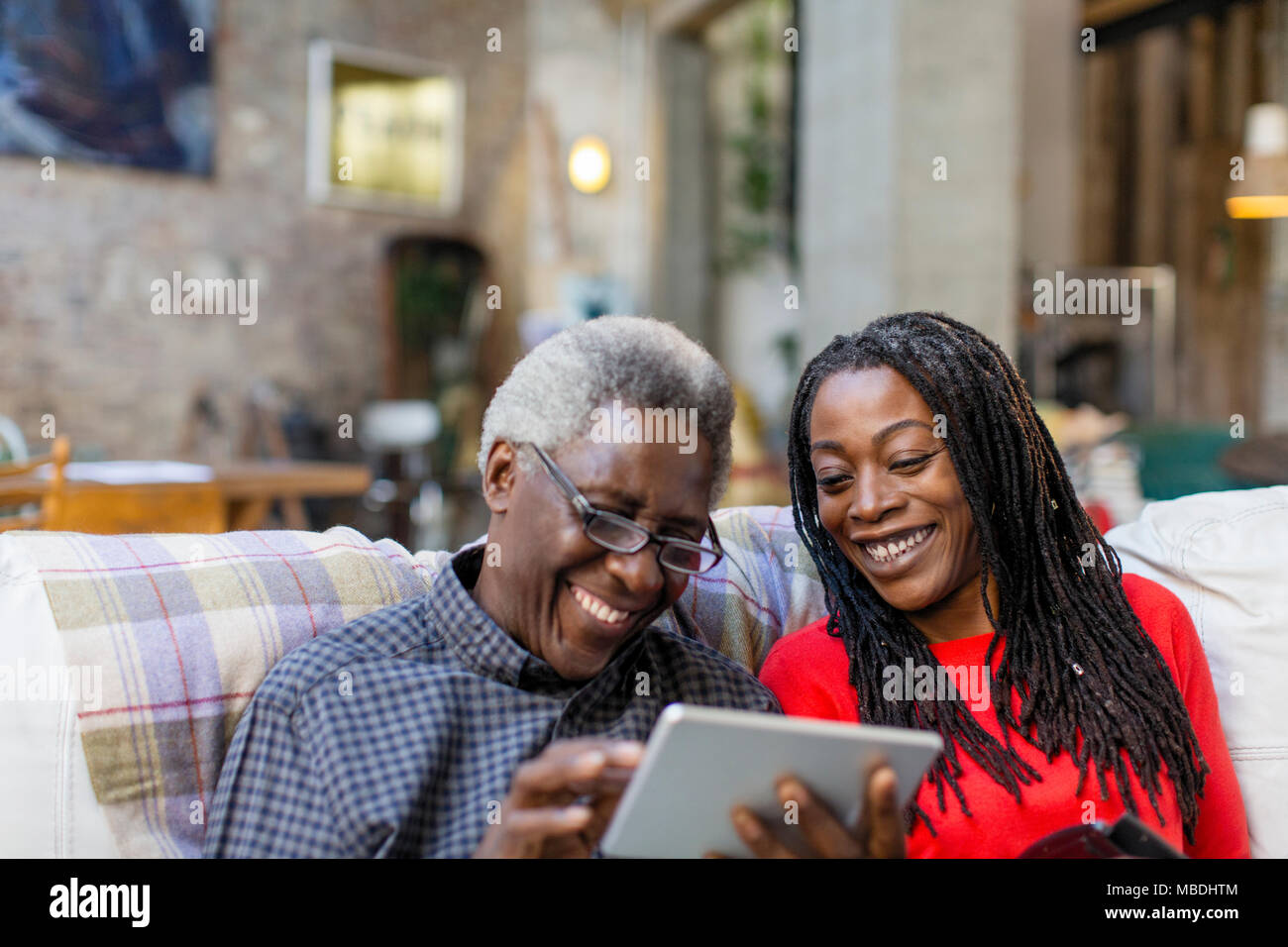 Sa fille adulte senior enseignement père comment utiliser digital tablet on sofa Banque D'Images