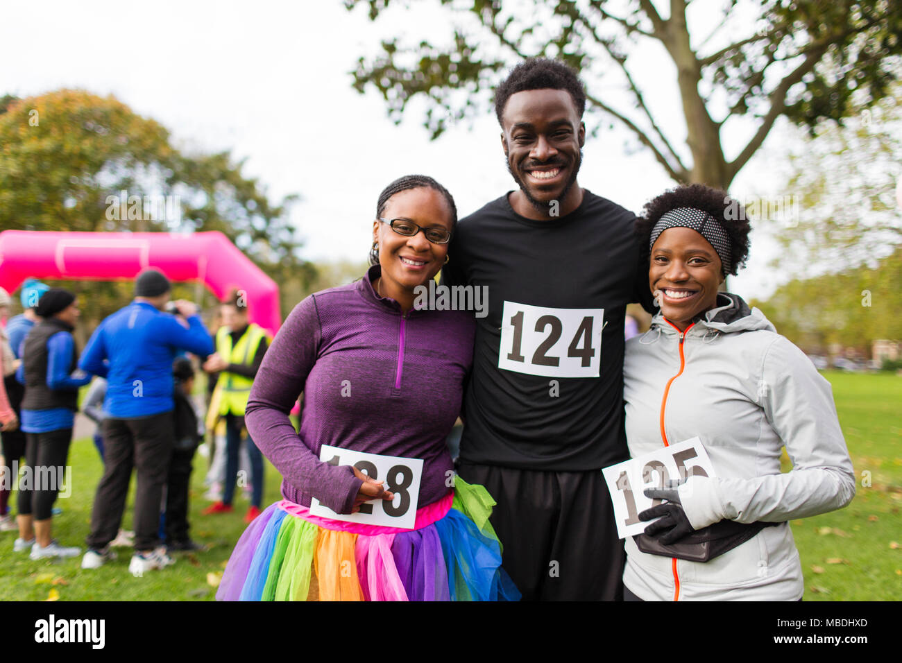 Portrait souriant, confiant avec la famille bavoirs marathon de charity run dans park Banque D'Images