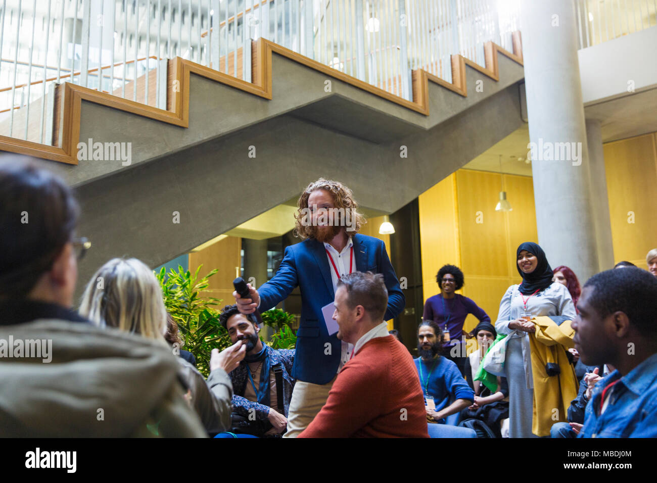 Male orateur microphone donnant à la femme en audience Banque D'Images