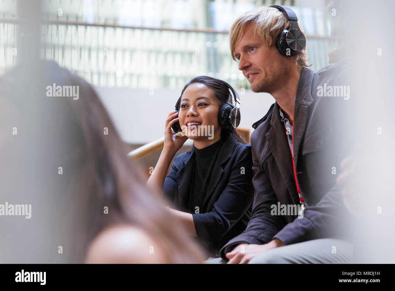 Smiling business people avec des écouteurs dans l'auditoire de la conférence Banque D'Images