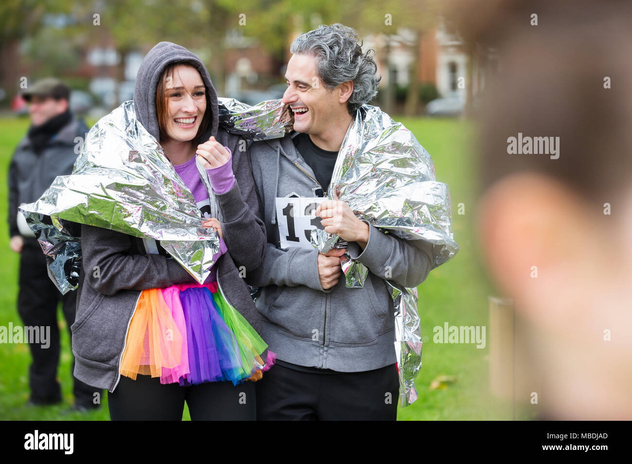 Couple heureux porteur enveloppé dans une couverture thermique de charity run dans park Banque D'Images