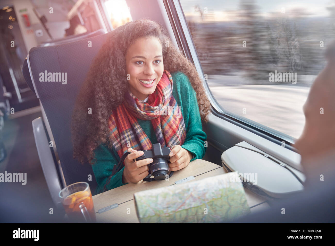 Souriante jeune femme avec appareil photo et carte Train de voyageurs d'équitation Banque D'Images